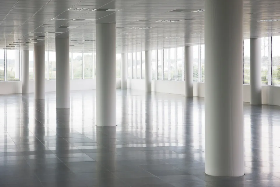 White round pillars in empty office building with windows across all walls and white floors and ceiling.